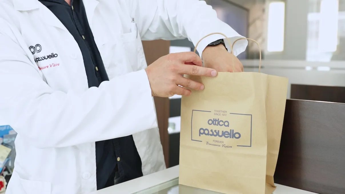 Addetto di Ottica Passuello che consegna una borsa con prodotti al banco.