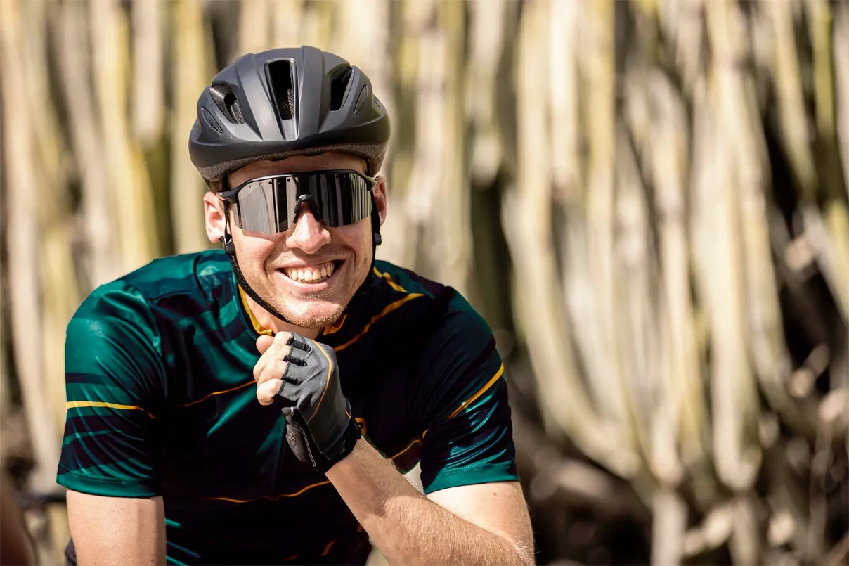 Ciclista sorridente con occhiali sportivi leggeri, performanti e protettivi ai raggi UV